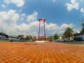 The red Giant Swing is a religious structure in Phra Nakhon with colorful flower garden in cloudy sky day.